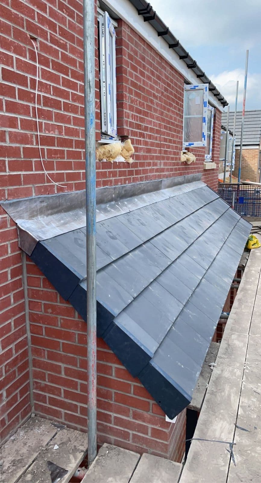 Tiled lean-to roof against a brick wall